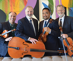 Alexander String Quartet in front of a colorful abstract painting which covers the entire wall behind them, Mamaroneck, New York